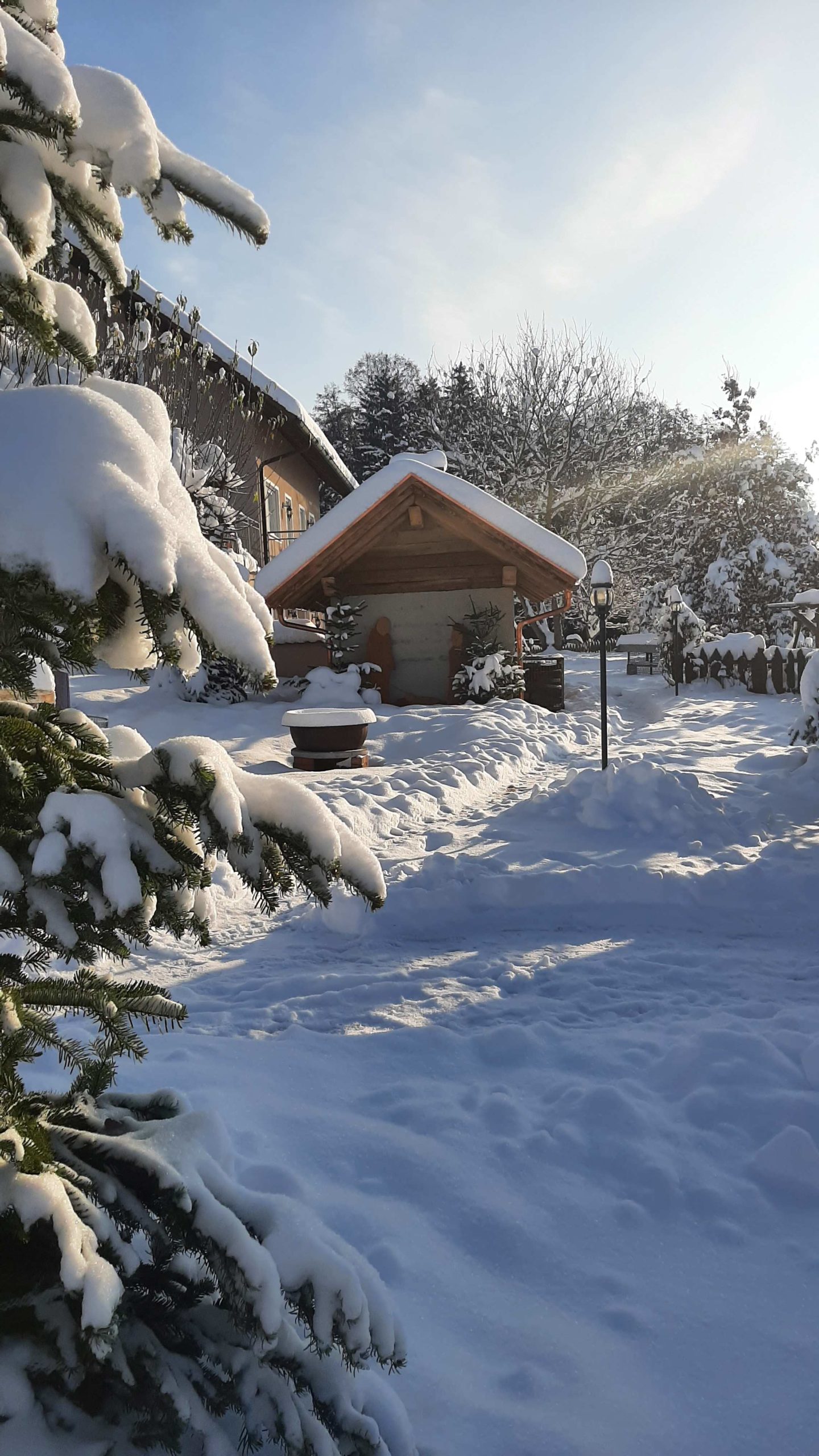 Schneebedeckter Garten, im Hintergrund ein Backofen mit Krippenfiguren